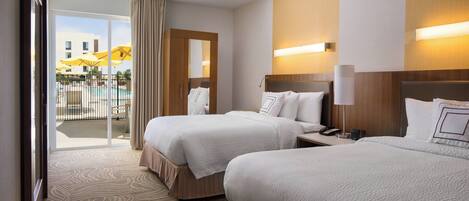 A hotel room with two beds, a large window with curtains, a view of a pool and umbrellas, and a wooden headboard with a lamp.