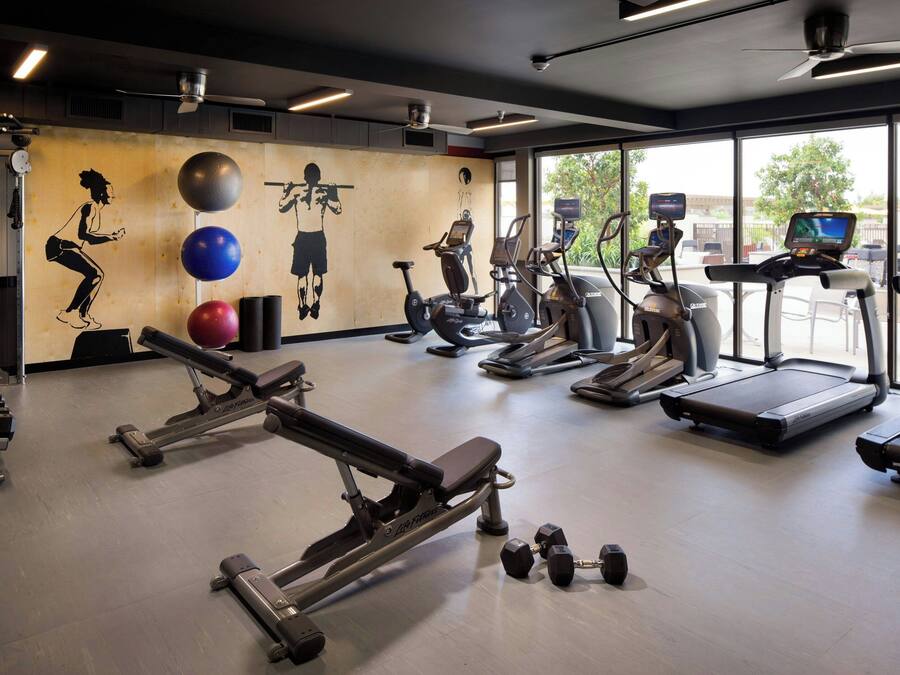 A gym with cardio equipment, weight machines, and a mural on the wall.
