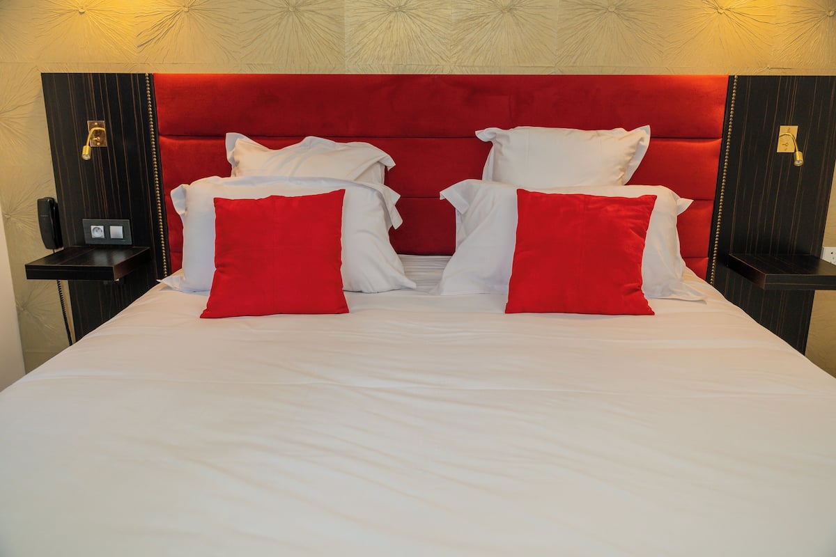 Una habitación de hotel con una cama grande, almohadas rojas y blancas, y un cabecero rojo.