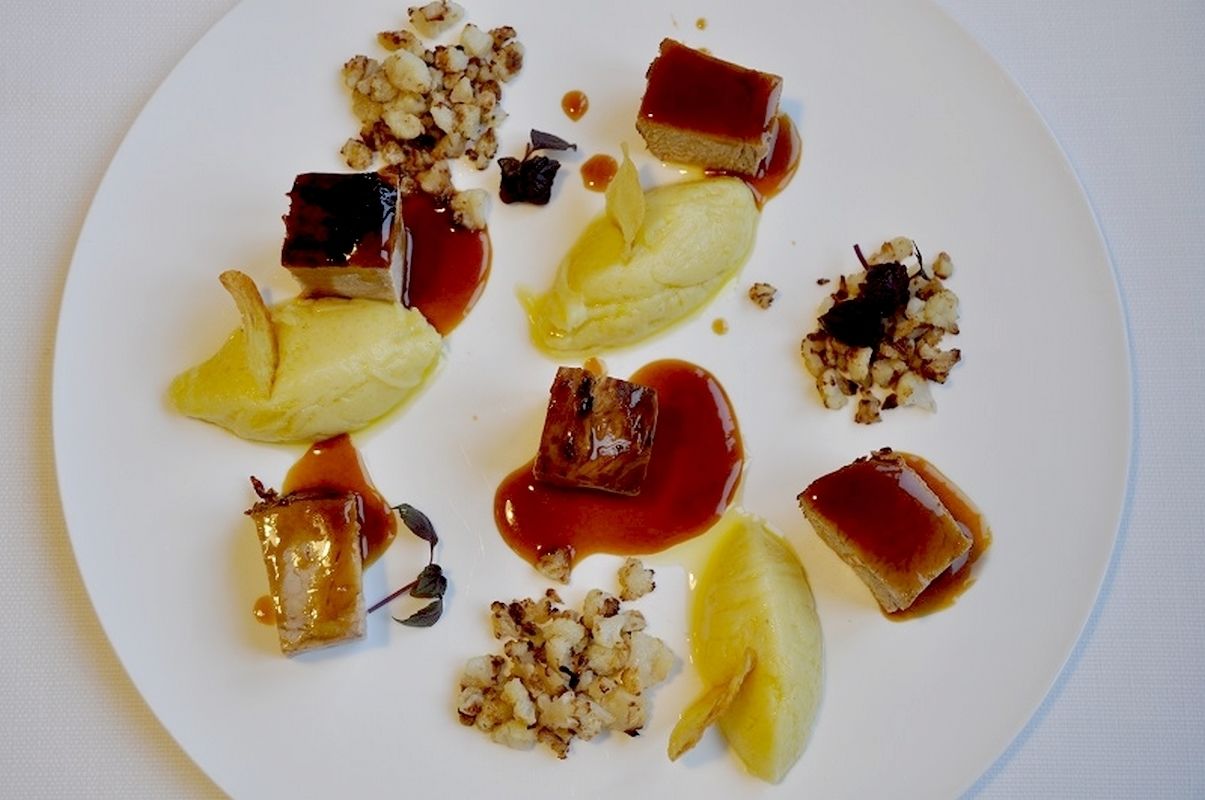 Un plat de postres amb diferents elements, incloent plàtans caramel·litzats, fruits secs i una porció de pastís.