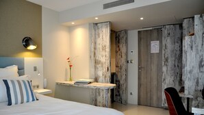 Una habitación de hotel con cama, mesita de noche, lámpara y un armario de madera.