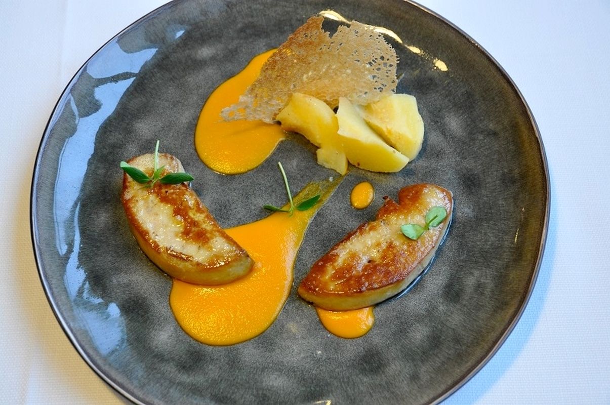 A plate with a piece of bread, two potato slices, and a sauce.