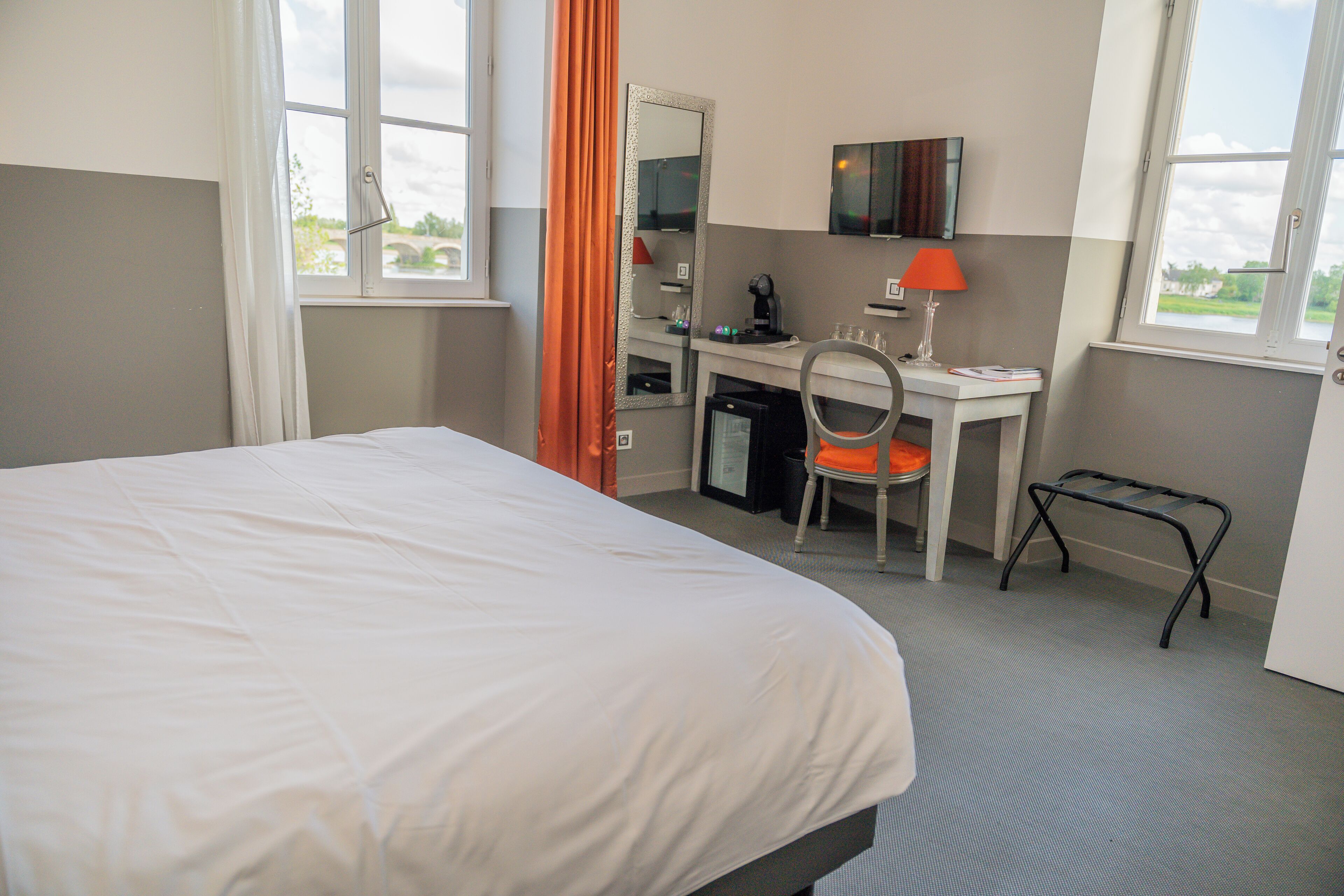 Een hotelkamer met een bed, bureau, stoel en een klein tafeltje.