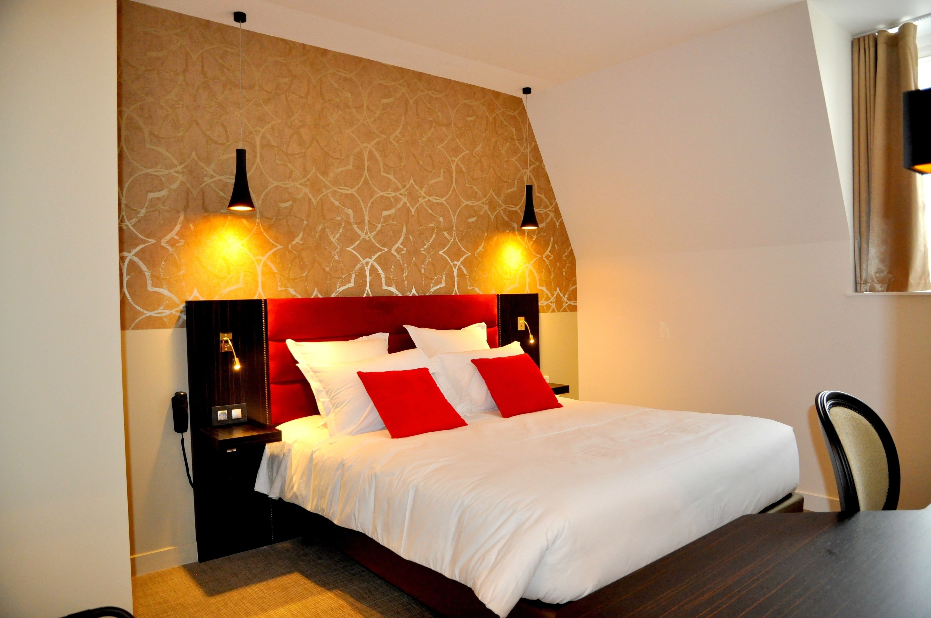 Una habitación de hotel con una cama grande, dos lámparas de noche, una mesita de noche y una silla.