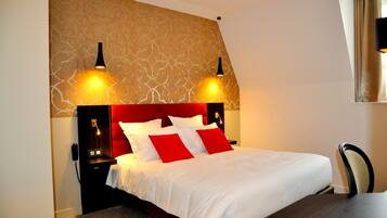 Una habitación de hotel con una cama grande, dos lámparas de noche, una mesita de noche y una silla.