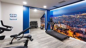 A gym with treadmills, dumbbells, and a cityscape mural. - 1881 Barcelona Rosellón Hotel (Barcelona)