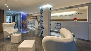 A modern hotel lobby with a reception desk, seating area, and a glass partition. - 1881 Barcelona Rosellón Hotel (Barcelona)