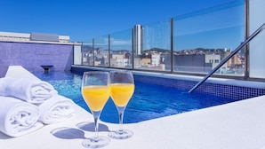 A rooftop pool with two glasses of orange juice and rolled towels. - 1881 Barcelona Rosellón Hotel (Barcelona)