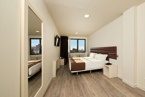 A modern hotel room with a large bed, a desk, and a view of the cityscape through the windows. - 1881 Barcelona Rosellón Hotel (Barcelona)