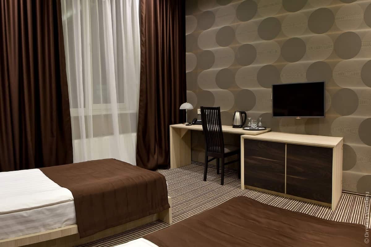 A hotel room with a bed, a desk with a chair, a television, and a coffee maker.