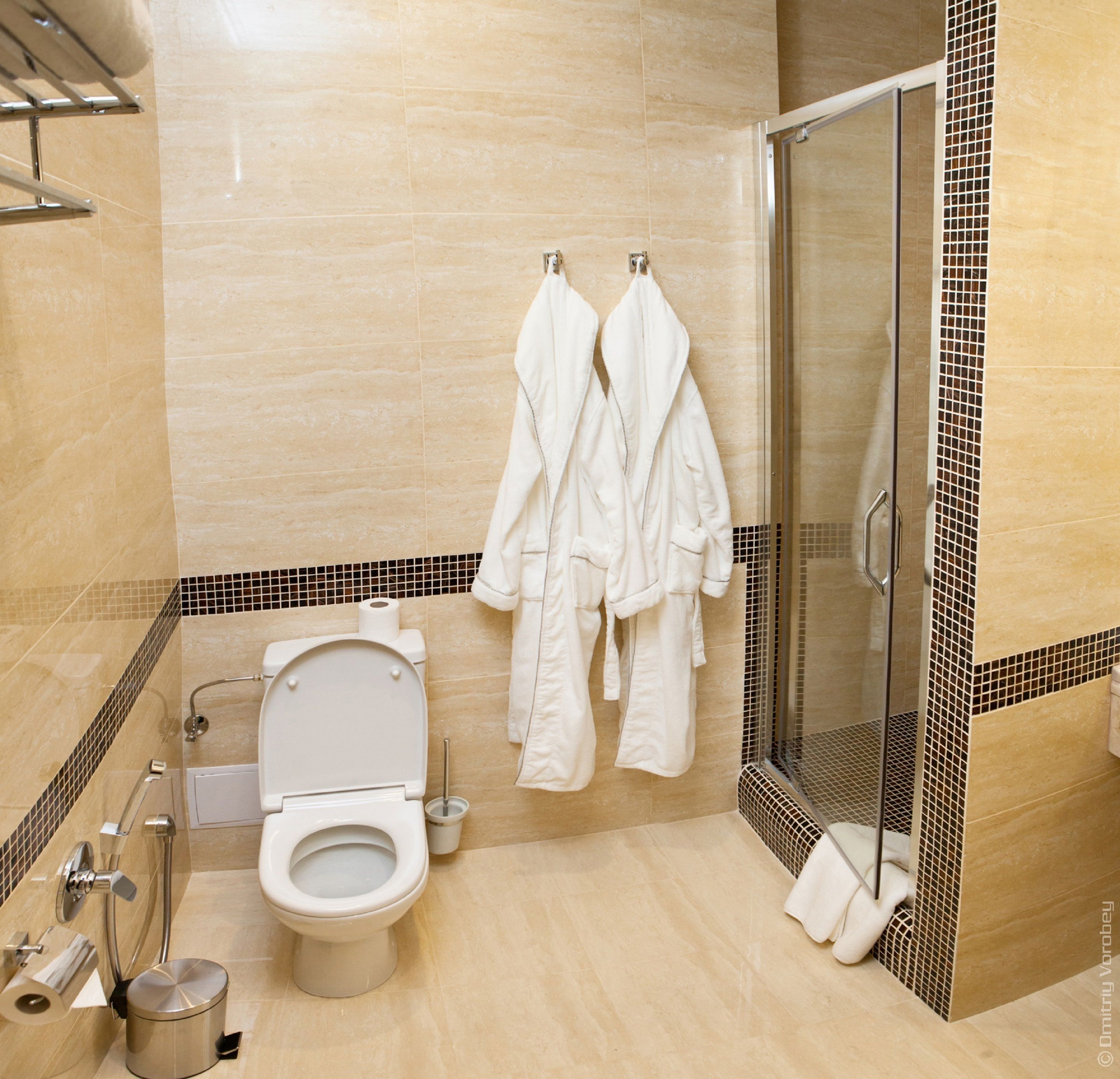 Un baño moderno con inodoro, ducha y cabina de ducha con paredes de vidrio.
