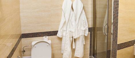 Un baño moderno con inodoro, ducha y cabina de ducha con paredes de vidrio.