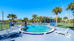 A swimming pool with blue tiles, surrounded by palm trees and a blue fence. - Rodeway Inn Bushnell (Bushnell)