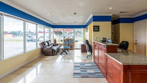 A hotel lobby with a reception desk, seating area, and large windows offering a view of the street. - Rodeway Inn Bushnell (Bushnell)