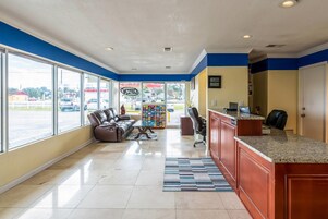 Un vestíbulo de hotel con mostrador de recepción, zona de estar y grandes ventanales con vistas a la calle.