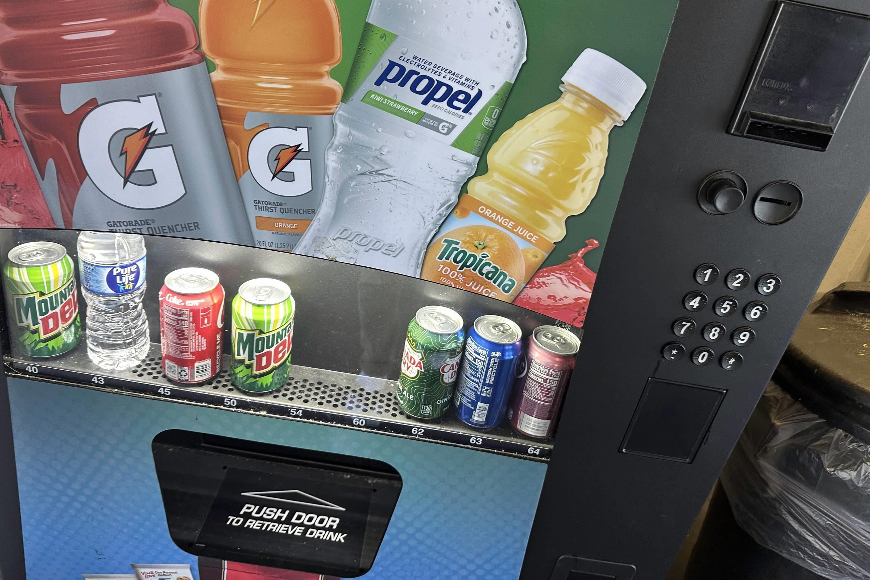 A vending machine with various drinks and a push door for retrieval.