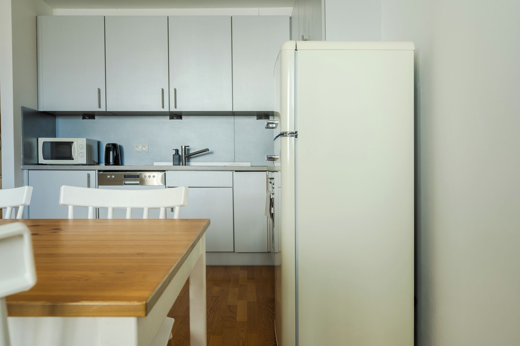 A compact kitchen with white cabinets, a microwave, a coffee maker, and a refrigerator.