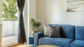 Een woonkamer met een blauwe bank, een potplant en een schilderij aan de muur.