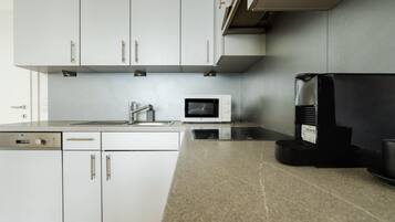 Una cucina moderna con mobili bianchi, un forno a microonde, una macchina per il caffè e una lavastoviglie.
