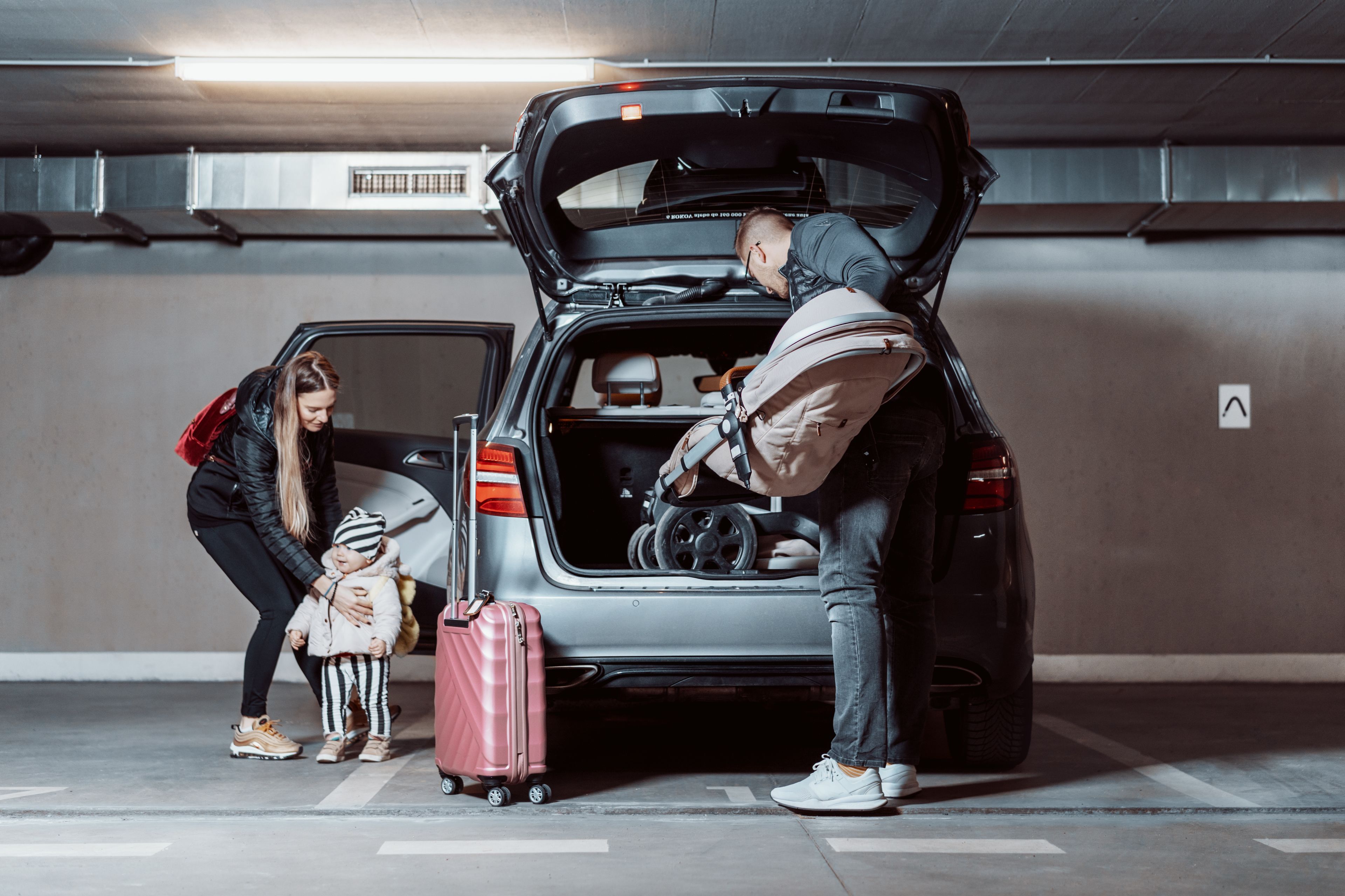 A family loading a car in a parking garage.