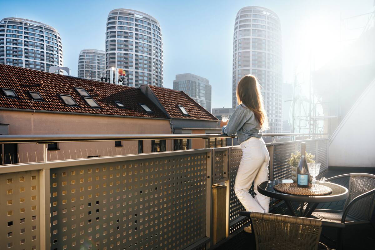 A balcony with a table and chairs, overlooking a cityscape with tall buildings.