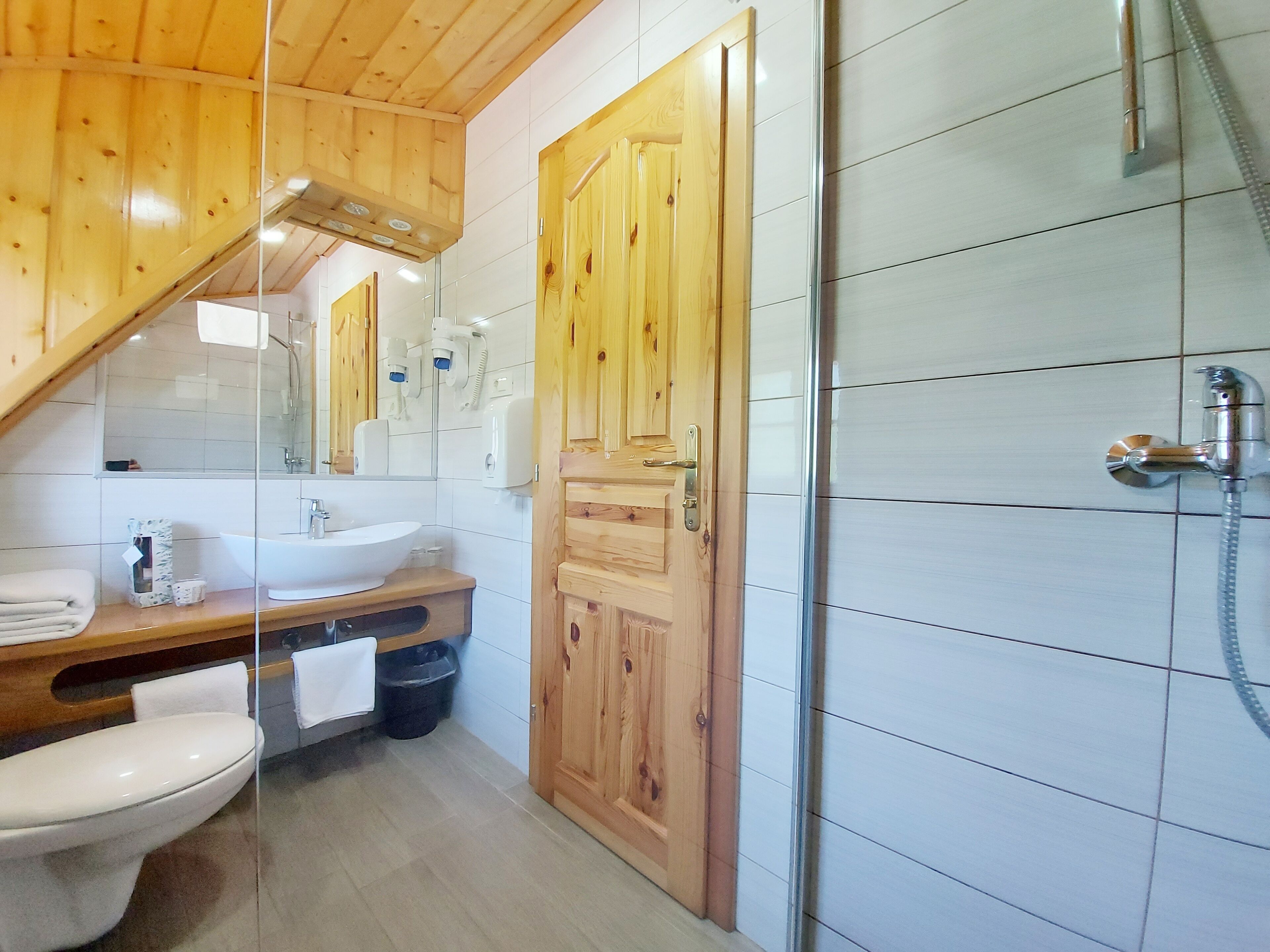 A bathroom with a wooden vanity, a sink, a toilet, and a shower area.