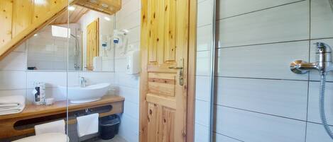 A bathroom with a wooden vanity, a sink, a toilet, and a shower area.
