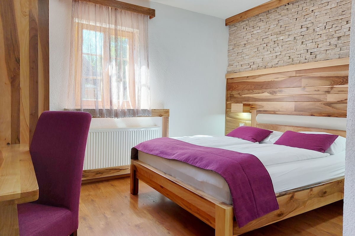 A bedroom with a wooden bed, a desk, and a chair.