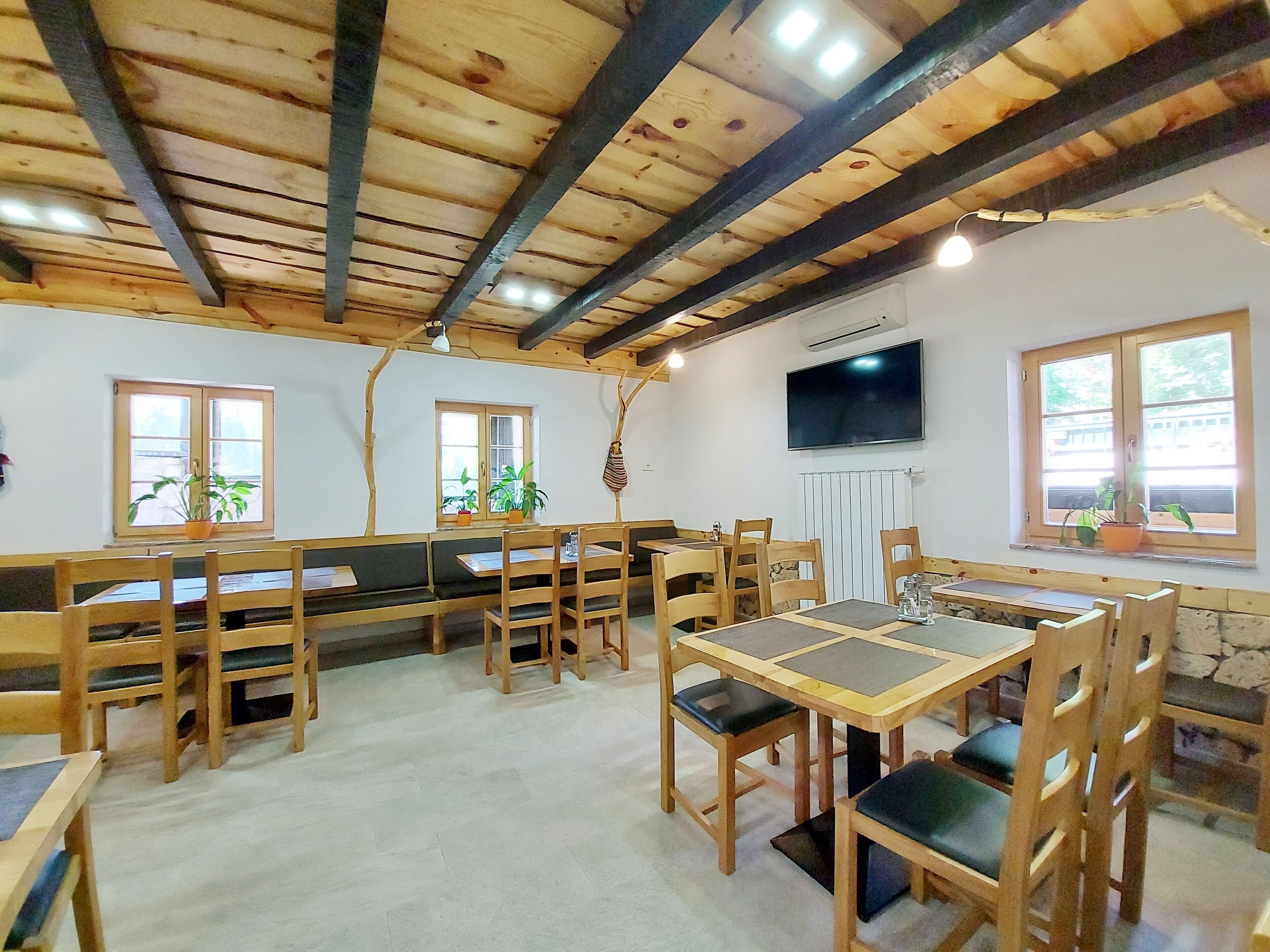 A rustic dining area with wooden furniture, stone walls, and large windows.