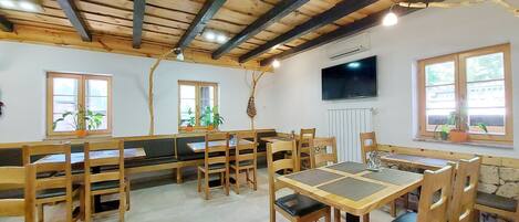 A rustic dining area with wooden furniture, stone walls, and large windows.
