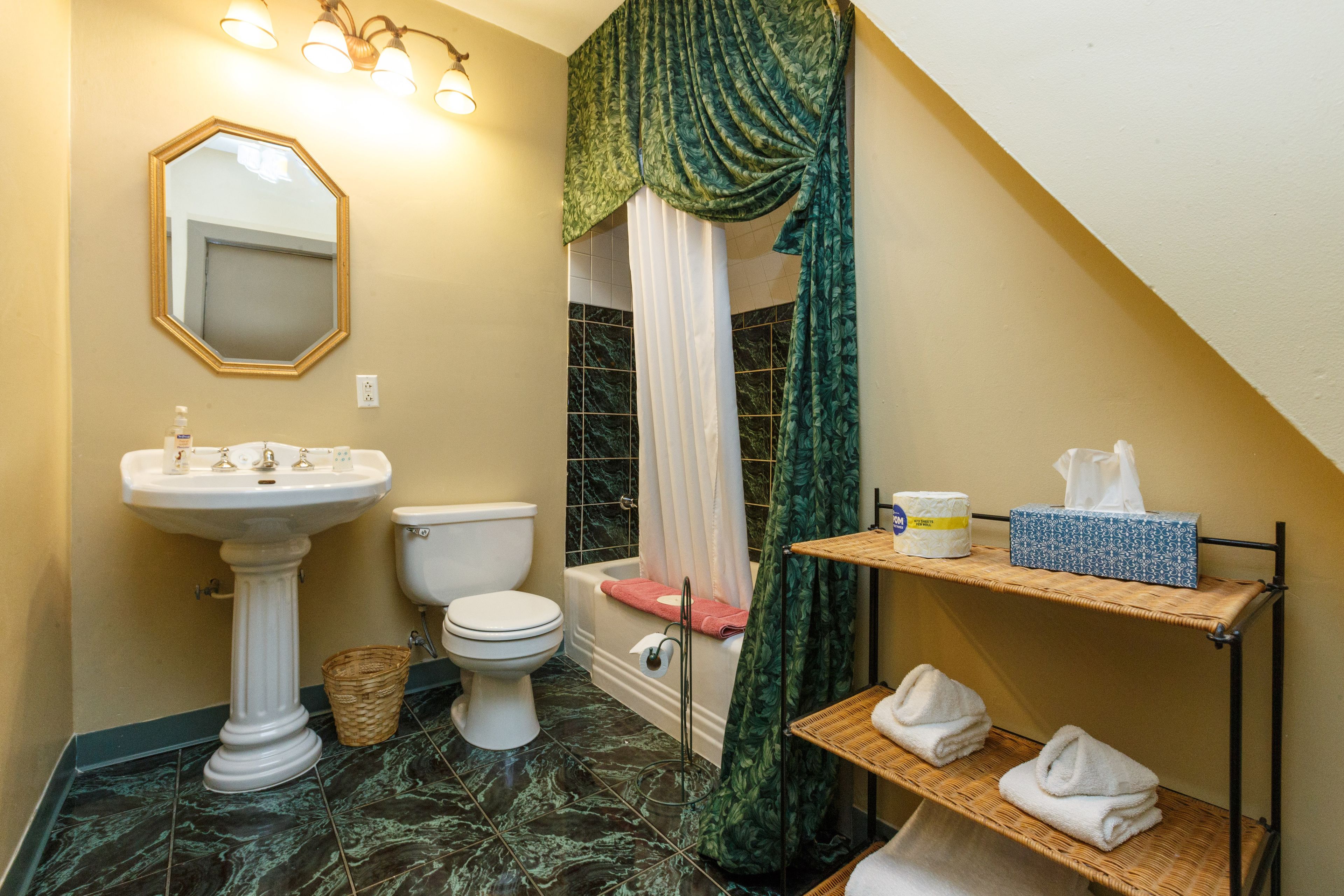A bathroom with a pedestal sink, toilet, bathtub, and a shower curtain.