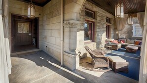 A stone building with a wooden ceiling and a covered porch. There are wicker chairs and a table on the porch. - Boggs Mansion (Pittsburgh)
