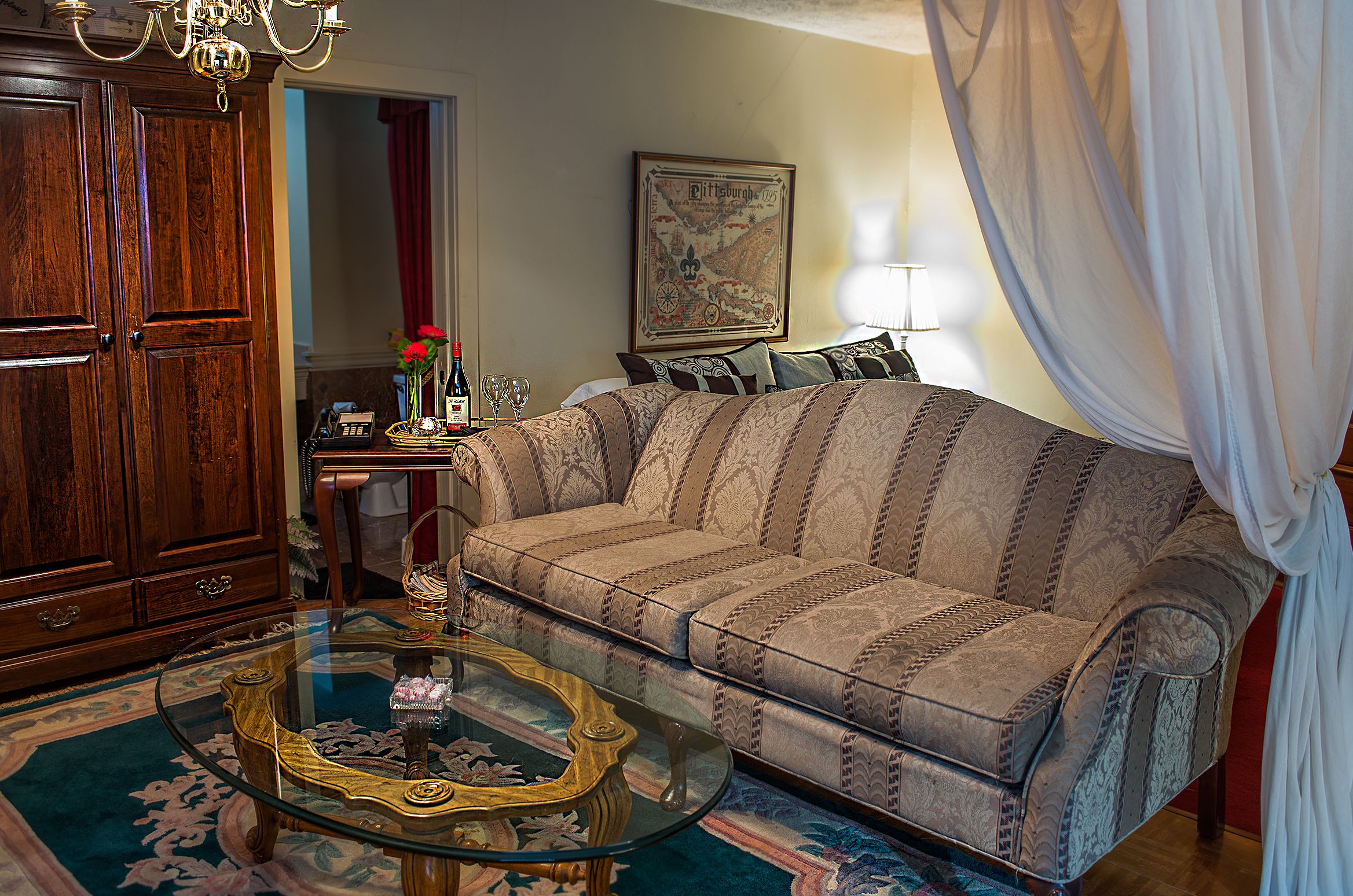 A living room with a sofa, a glass coffee table, a wooden cabinet, and a map on the wall.