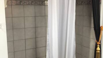 Ein Badezimmer mit einer Badewanne, einem weißen Duschvorhang und einem schwarzen und goldenen Zierstreifen.