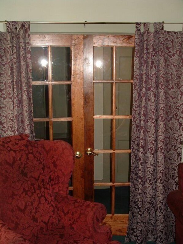 A room with a wooden door with glass panels, red patterned upholstery, and matching curtains. - Boggs Mansion (Pittsburgh)