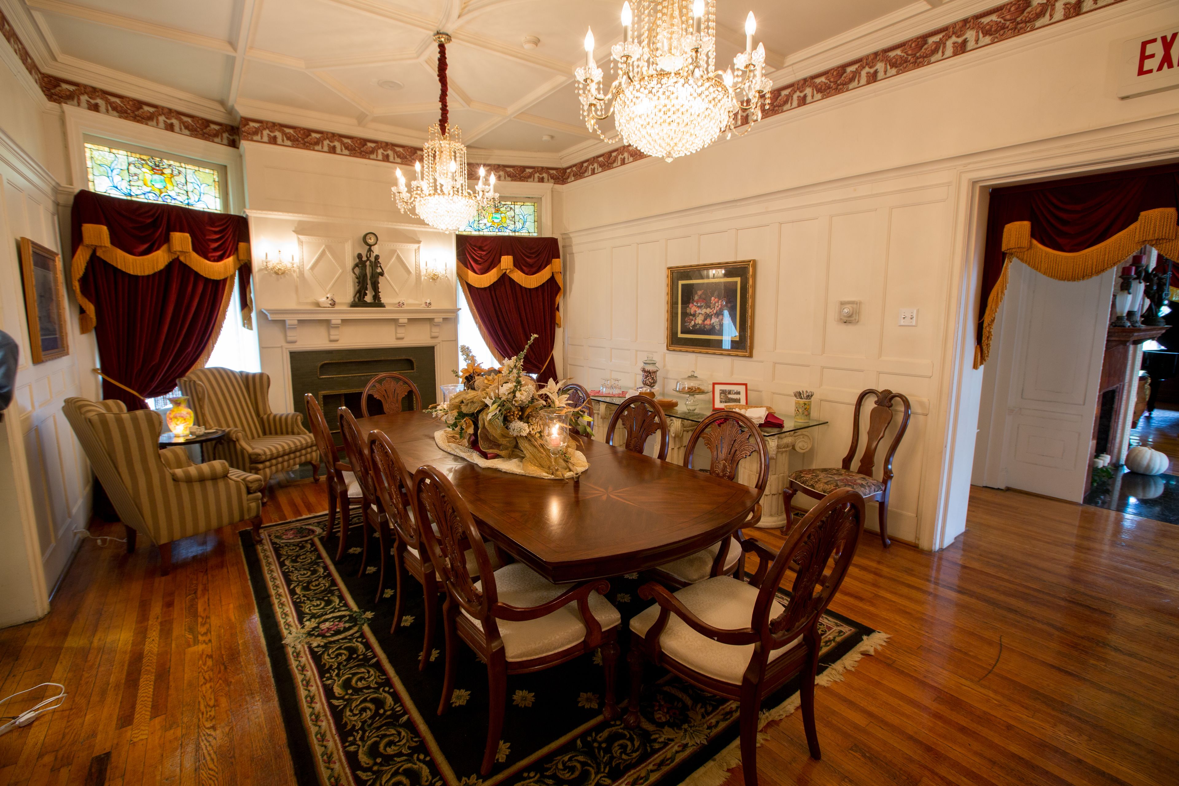 A formal dining room with a large wooden table, upholstered chairs, and a chandelier.