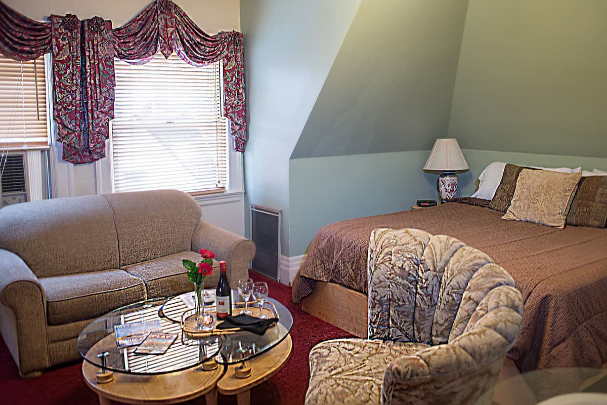 A bedroom with a bed, a sofa, a coffee table, and a lamp.