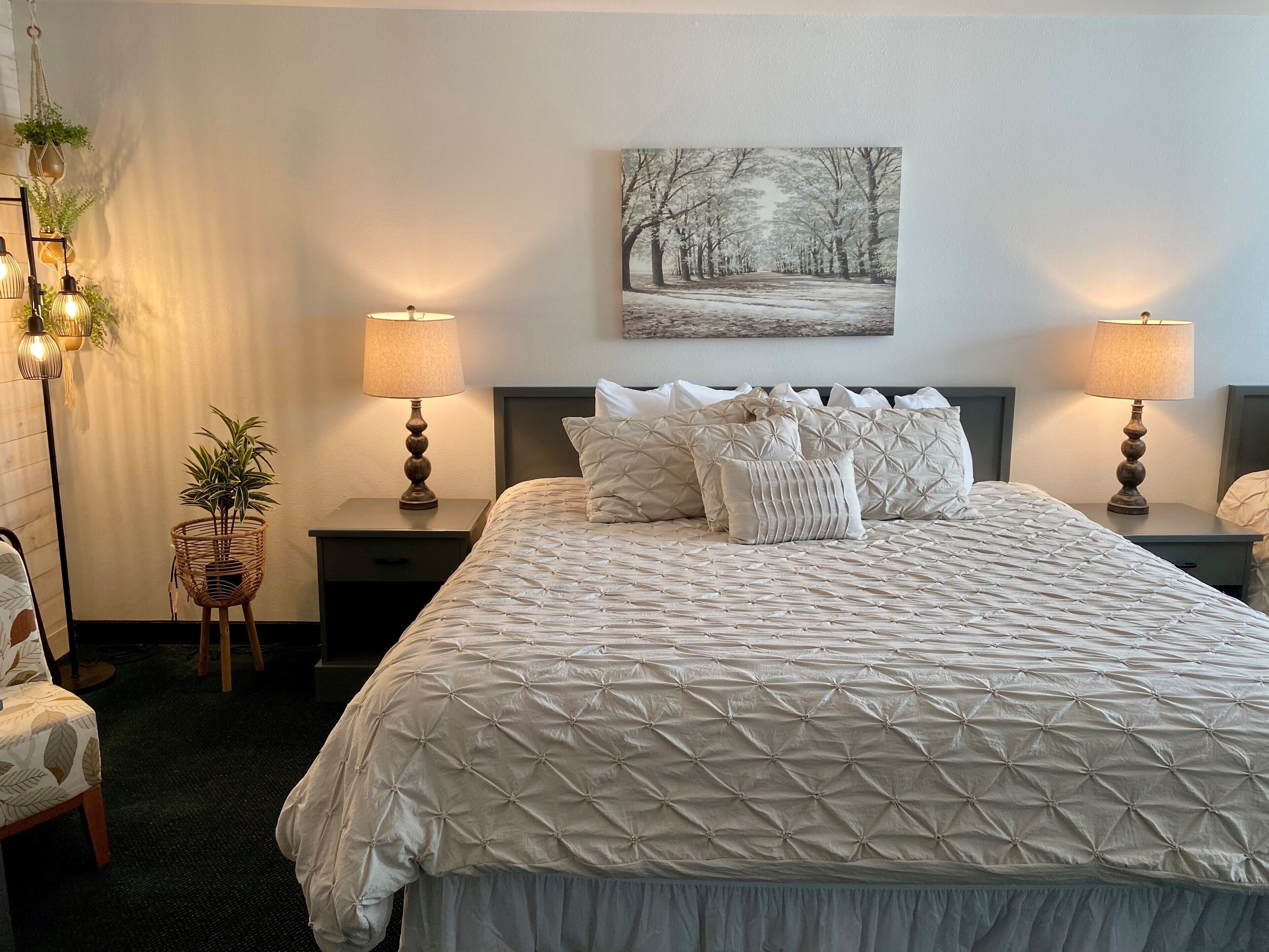 Une chambre à coucher bien rangée, avec un grand lit, deux tables de chevet et un tableau accroché au mur.
