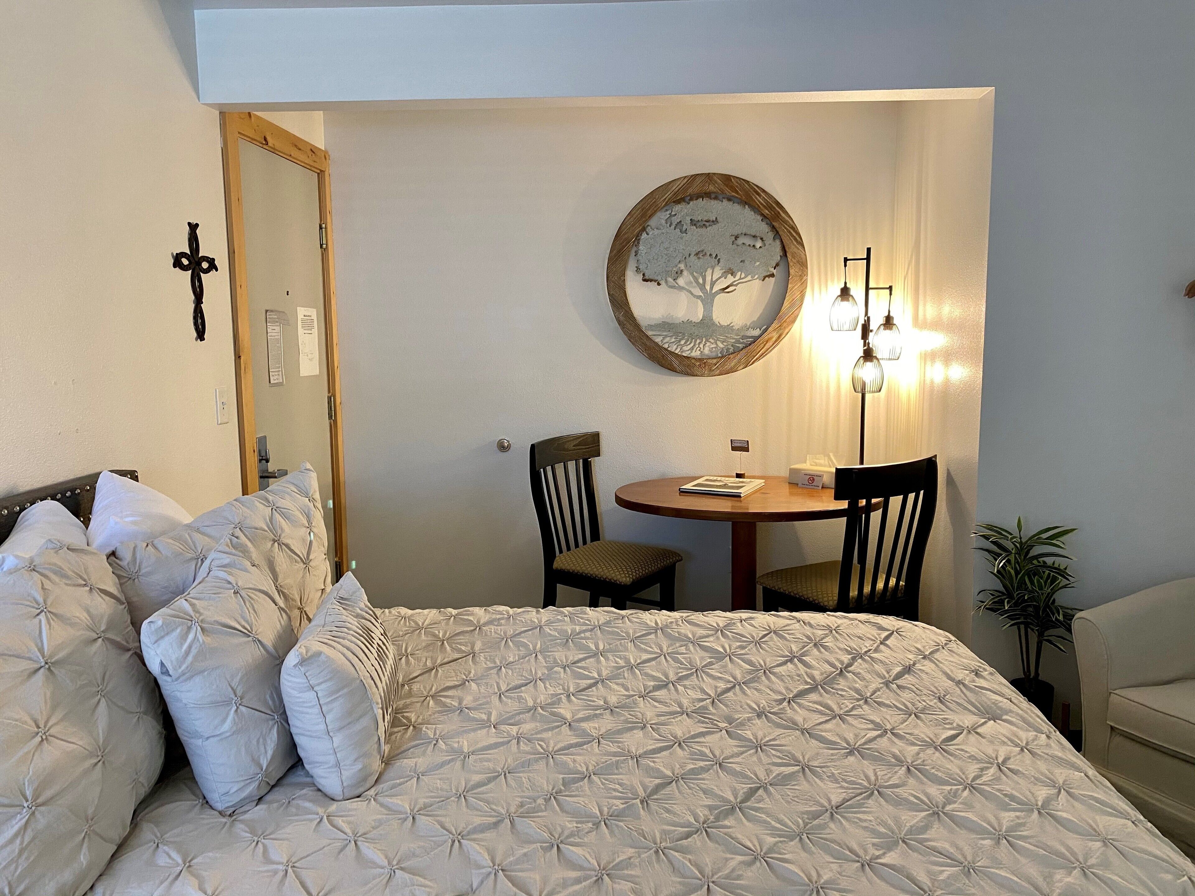 Ein Schlafzimmer mit einem Bett, einem runden Tisch mit Stühlen, einer Wandlampe und einem Spiegel.
