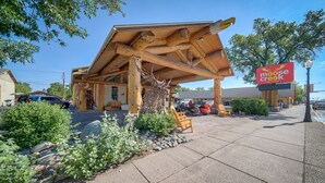 A rustic building with a wooden exterior and a large elk sculpture in front. - Moose Creek Lodge & Suites (Cody)
