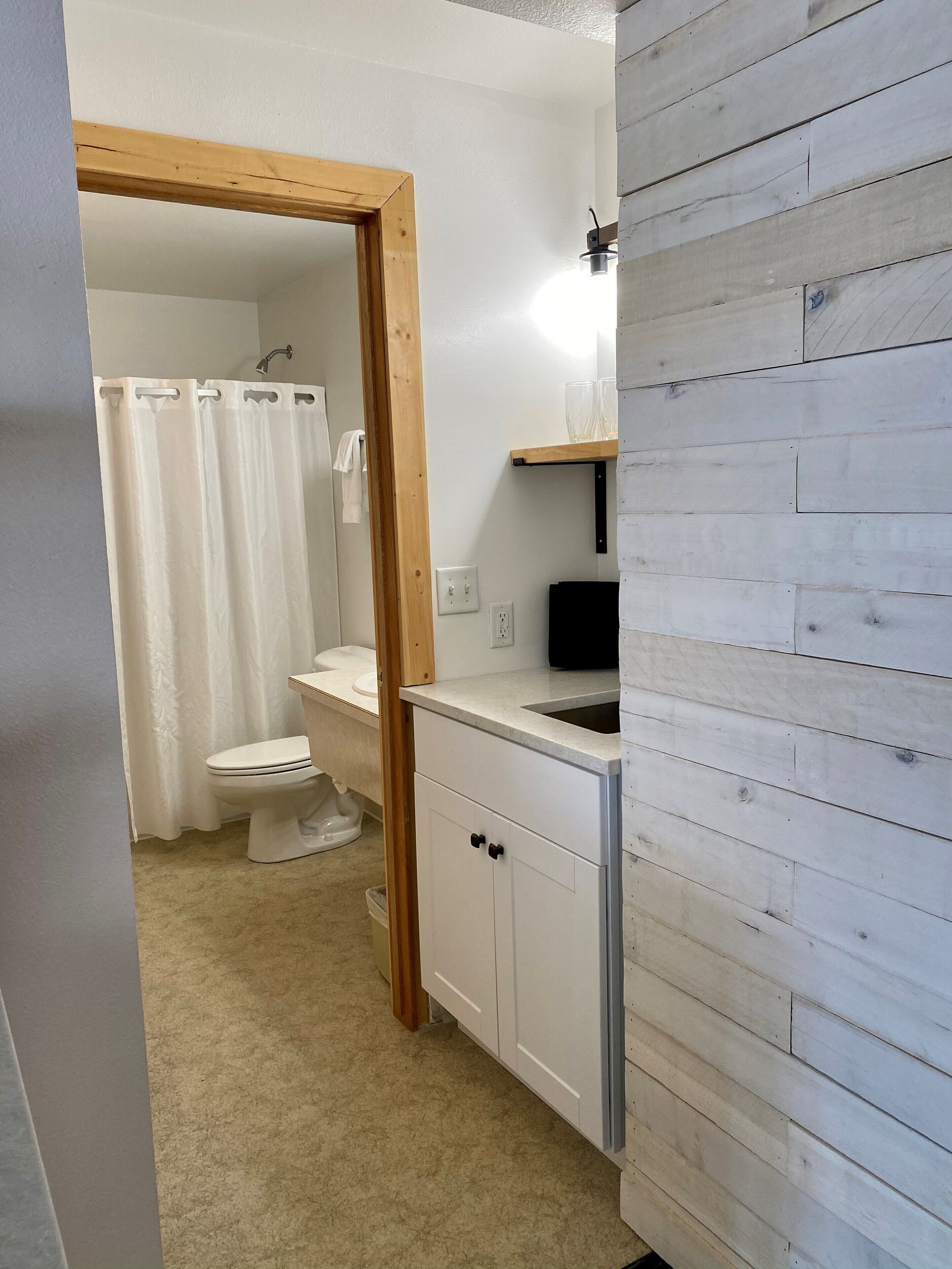 Een badkamer met toilet, douchegordijn en wastafel met spiegel.