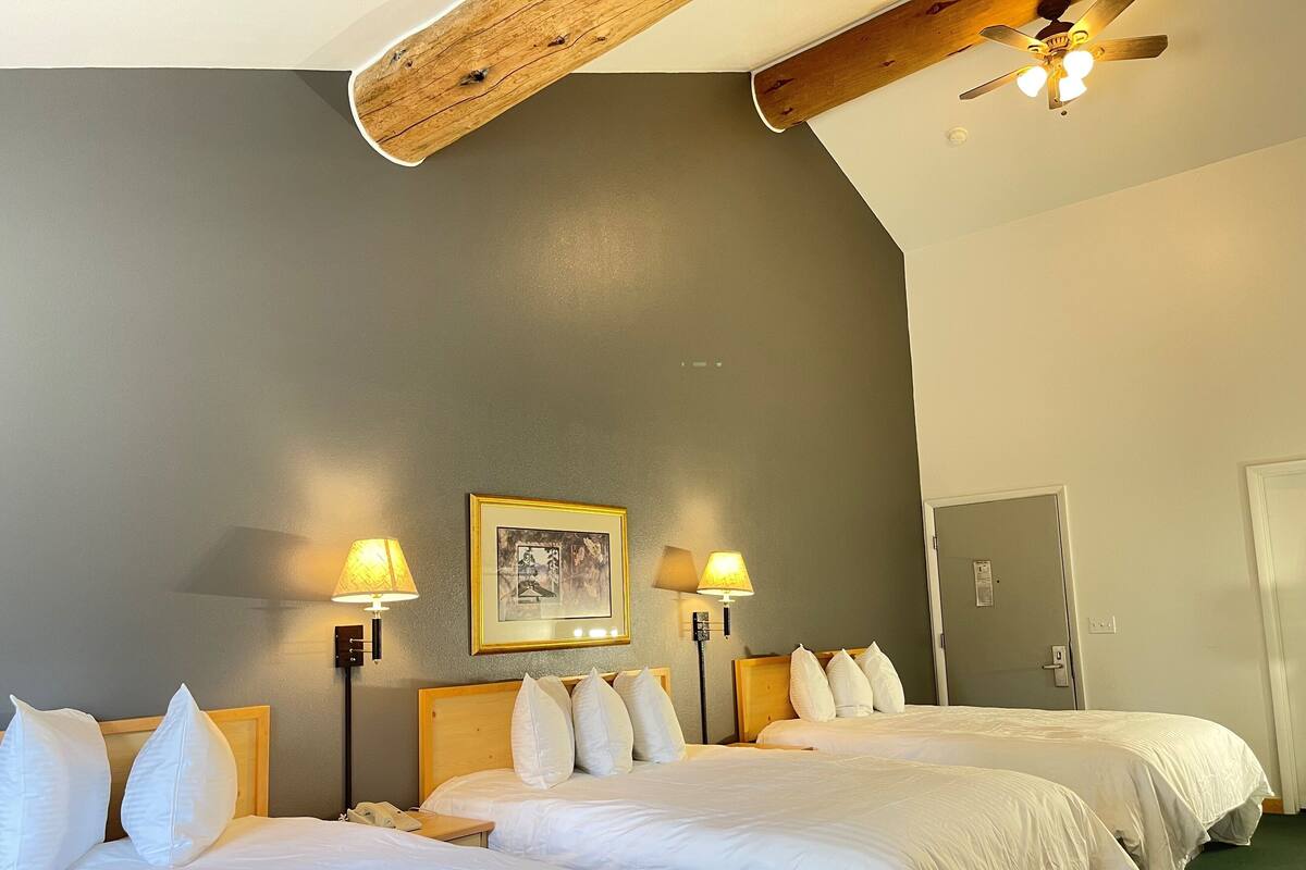 A hotel room with two beds, a ceiling fan, a framed picture on the wall, and two bedside lamps.