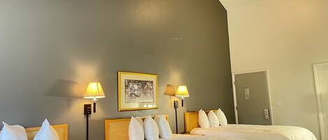 A hotel room with two beds, a ceiling fan, a framed picture on the wall, and two bedside lamps.