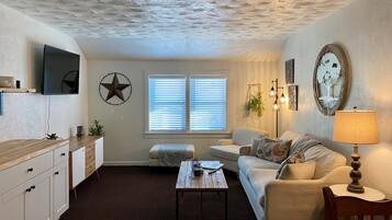 A cozy living room with a wooden coffee table, a sofa, a TV mounted on the wall, and a star decoration.