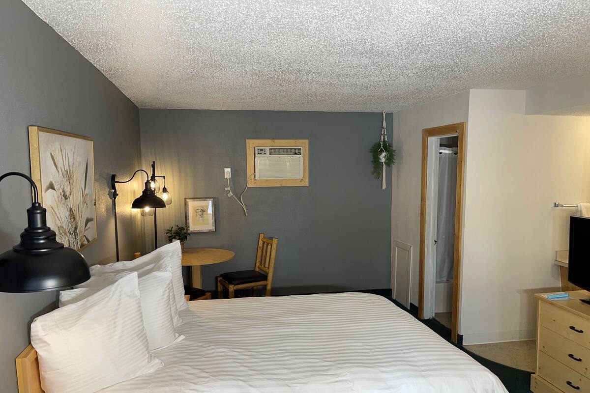 A neatly arranged bedroom with a large bed, a desk, and a chair.
