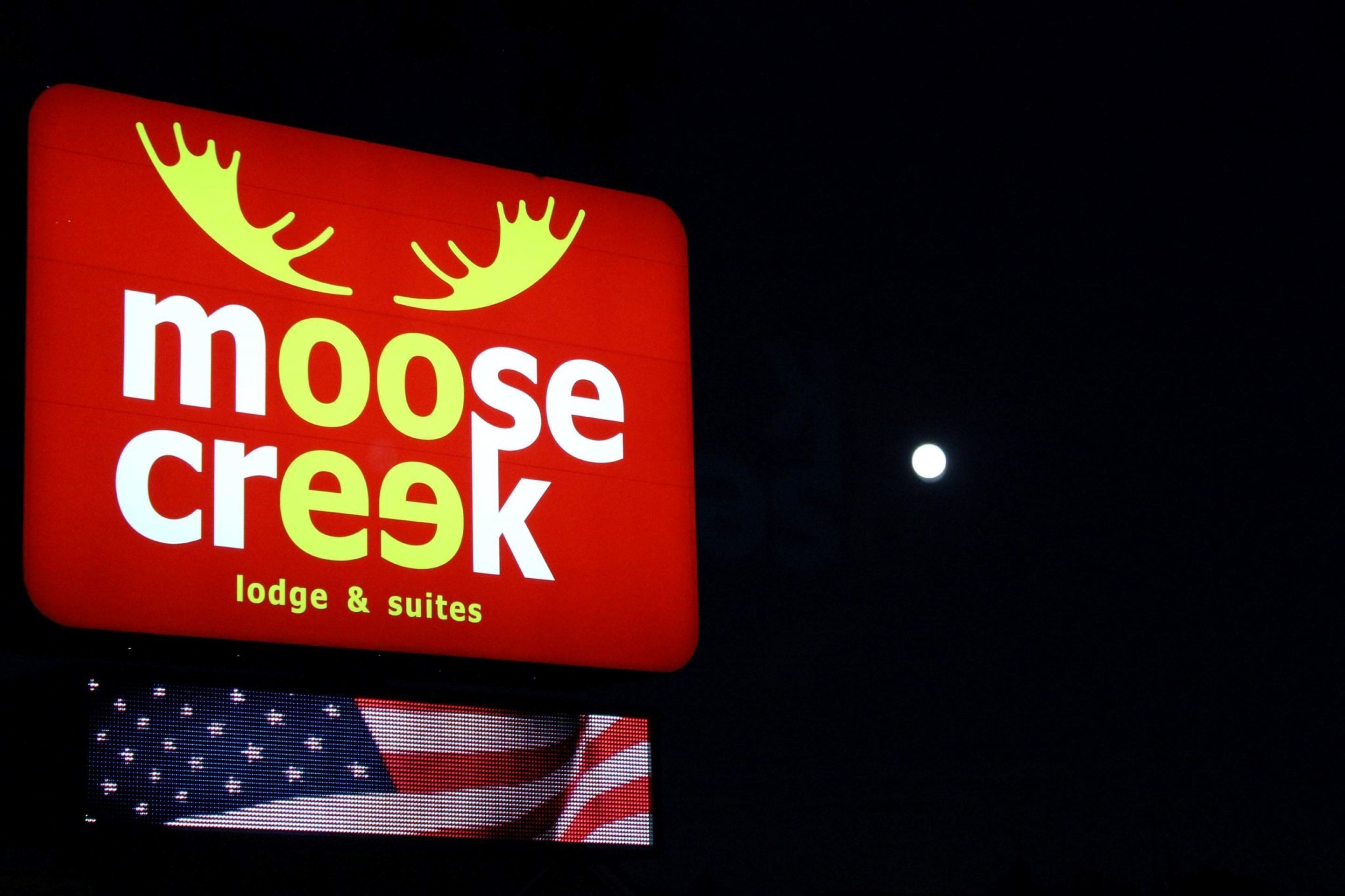 A red sign with the text "moose creek lodge & suites" and a moose silhouette.