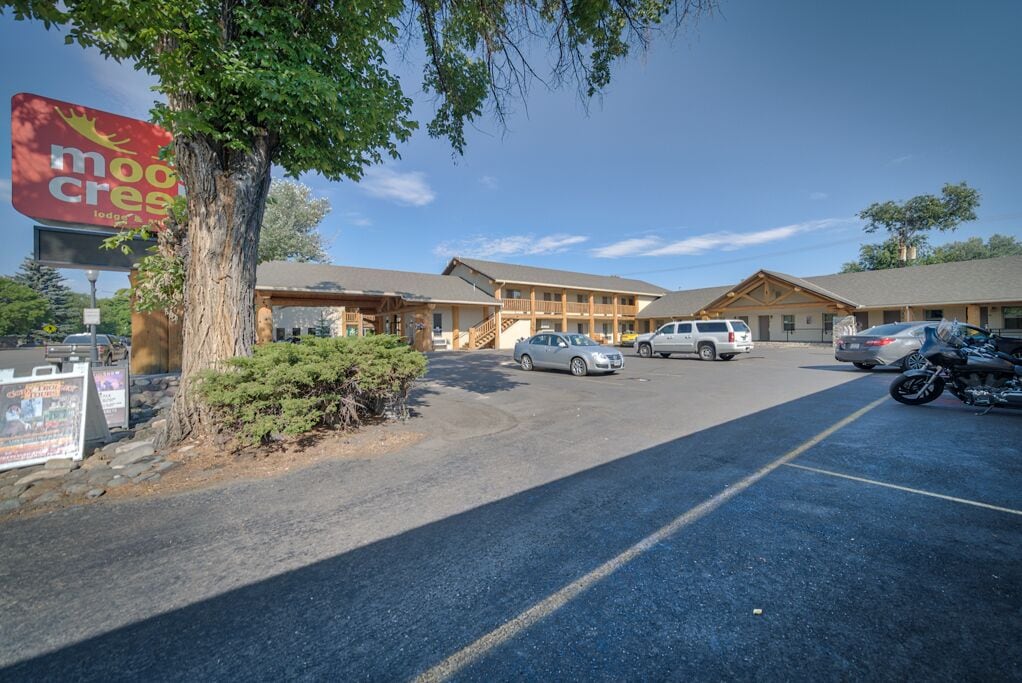 A motel with a large sign, a parking lot, and a building with a covered entrance.