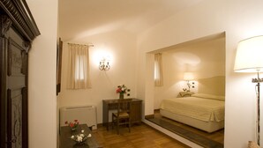 Un dormitorio con cama, mesita de noche, lámpara y un escritorio pequeño con silla.