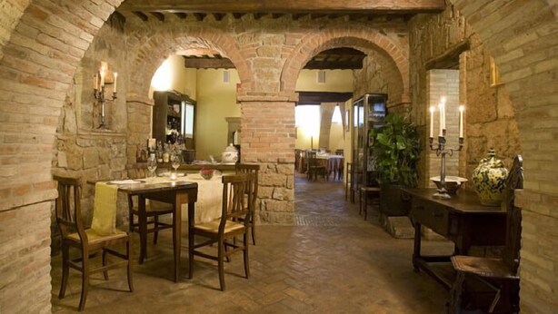 Un comedor rústico con arcos de ladrillo, mesas y sillas de madera.