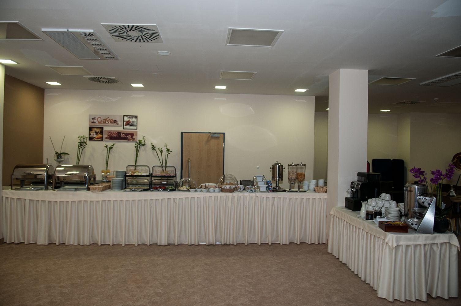 A buffet setup with various food stations, including a coffee machine and a fruit display.